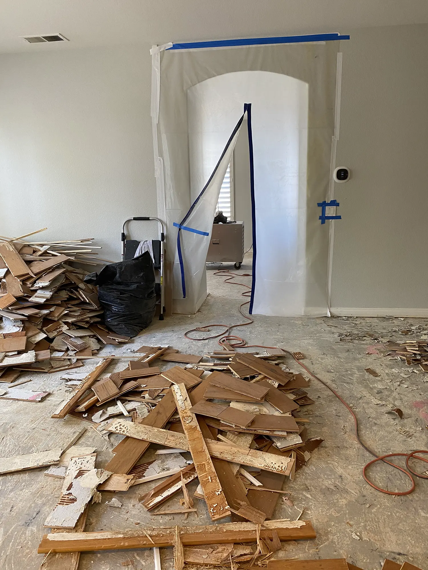 Demolition of warped wood flooring during water-damage remediation in a Houston home interior